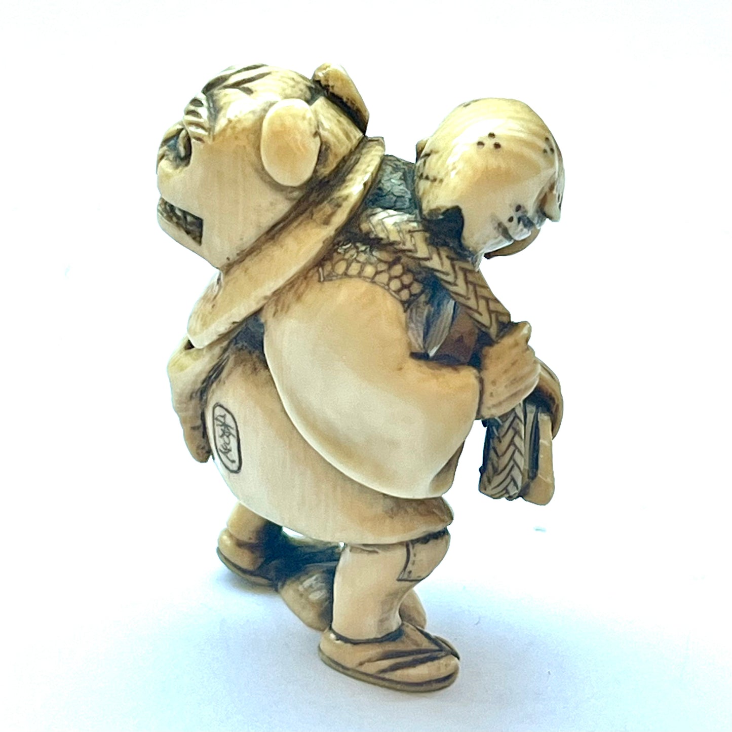 Antique Japanese Meiji Period ivory netsuke depicting an old man carrying a shishi, signed by Hideyuki