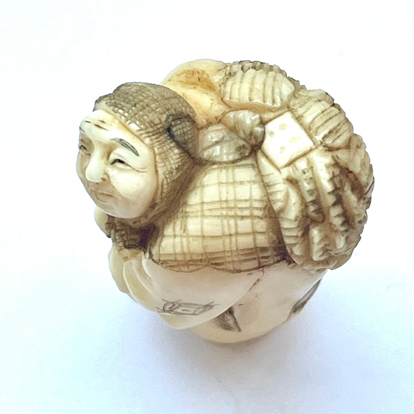 Antique Japanese Meiji Period ivory netsuke depicting an old lady carrying bundles. Signed by 玉之 (Gyokuyuki)