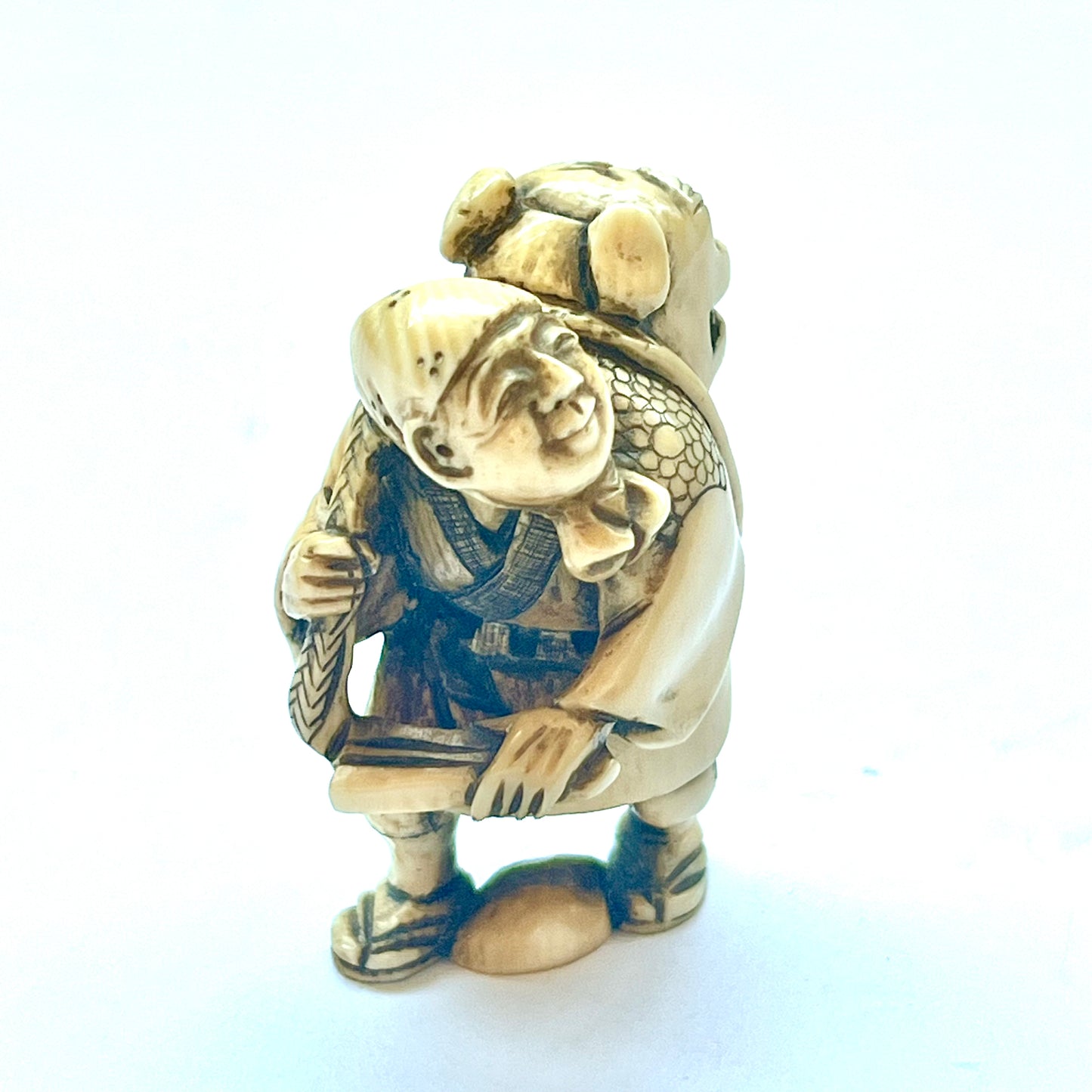 Antique Japanese Meiji Period ivory netsuke depicting an old man carrying a shishi, signed by Hideyuki