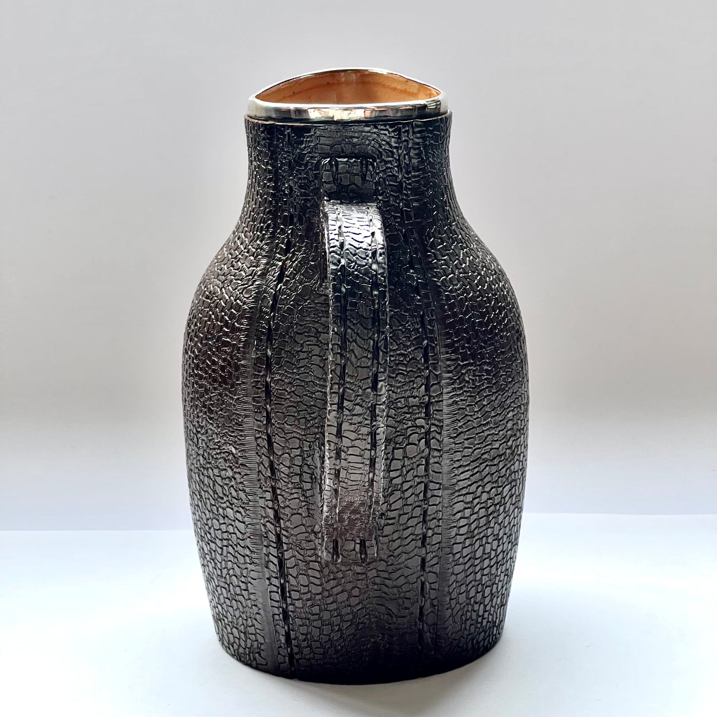 Victorian Doulton Lambeth Leather Ware Slaters blackjack jug with Sterling Silver Rim, marked for London, 1892, Cornelius Desormeaux Saunders & James Francis Hollings (Frank) Shepherd.