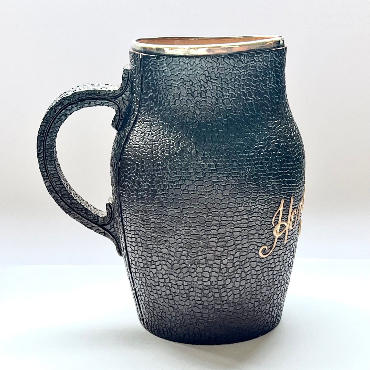 Victorian Doulton Lambeth Leather Ware Slaters blackjack jug with Sterling Silver Rim, marked for London, 1892, Cornelius Desormeaux Saunders & James Francis Hollings (Frank) Shepherd.