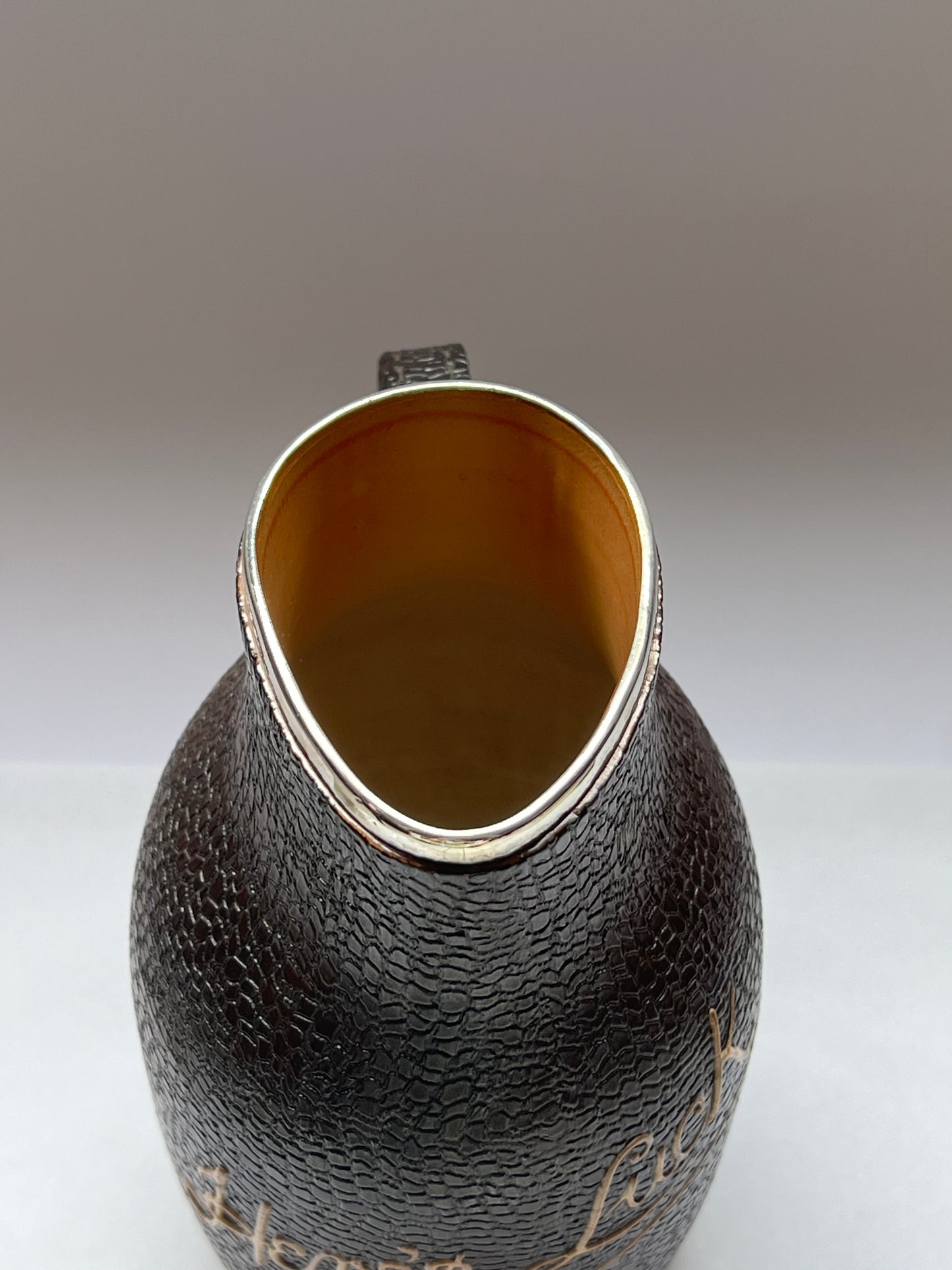 Victorian Doulton Lambeth Leather Ware Slaters blackjack jug with Sterling Silver Rim, marked for London, 1892, Cornelius Desormeaux Saunders & James Francis Hollings (Frank) Shepherd.