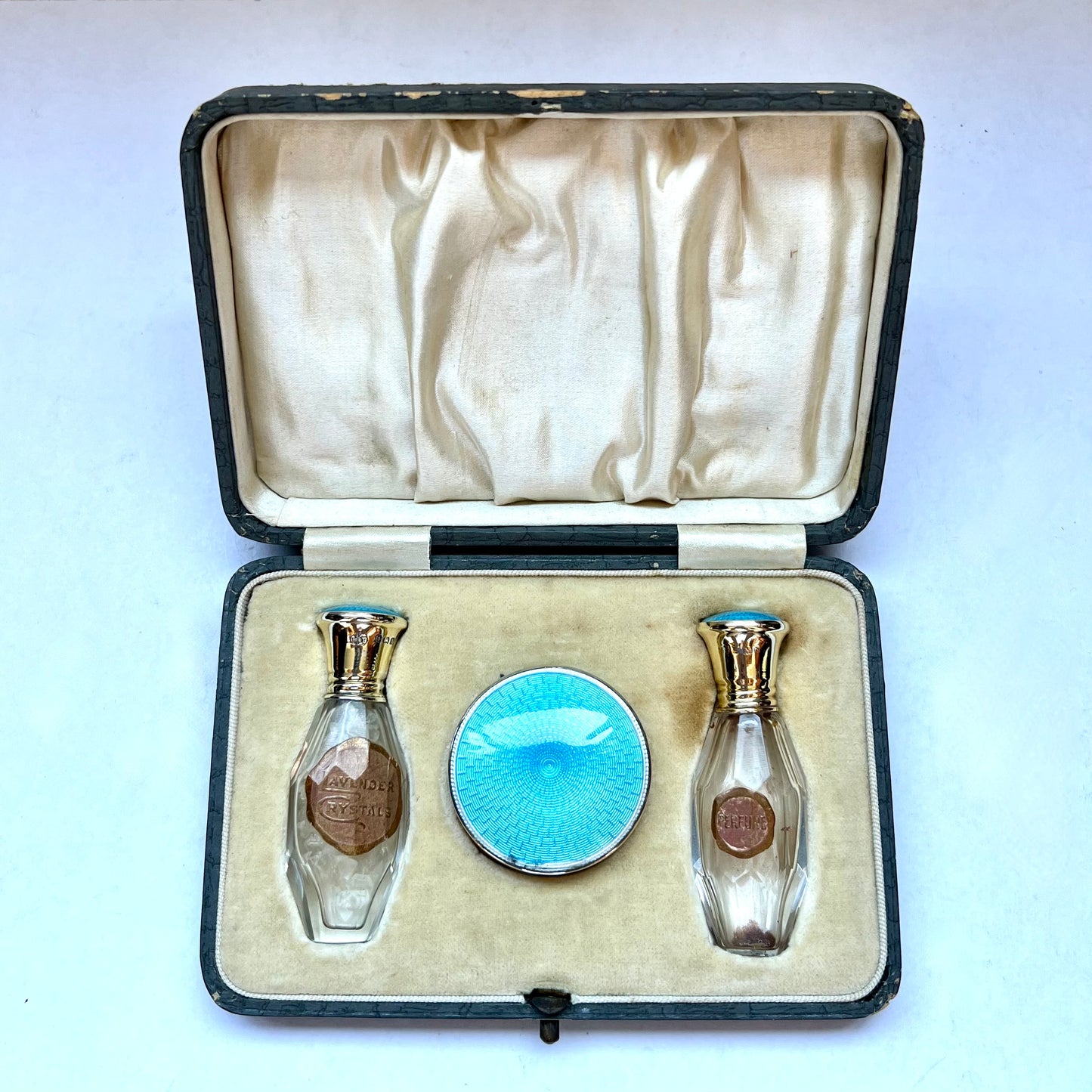 Antiguo neceser de viaje Art Déco con esmalte guilloché azul verdoso y dorado sobre plata de ley. Cristales de lavanda, frasco de perfume y borla de polvos sueltos.