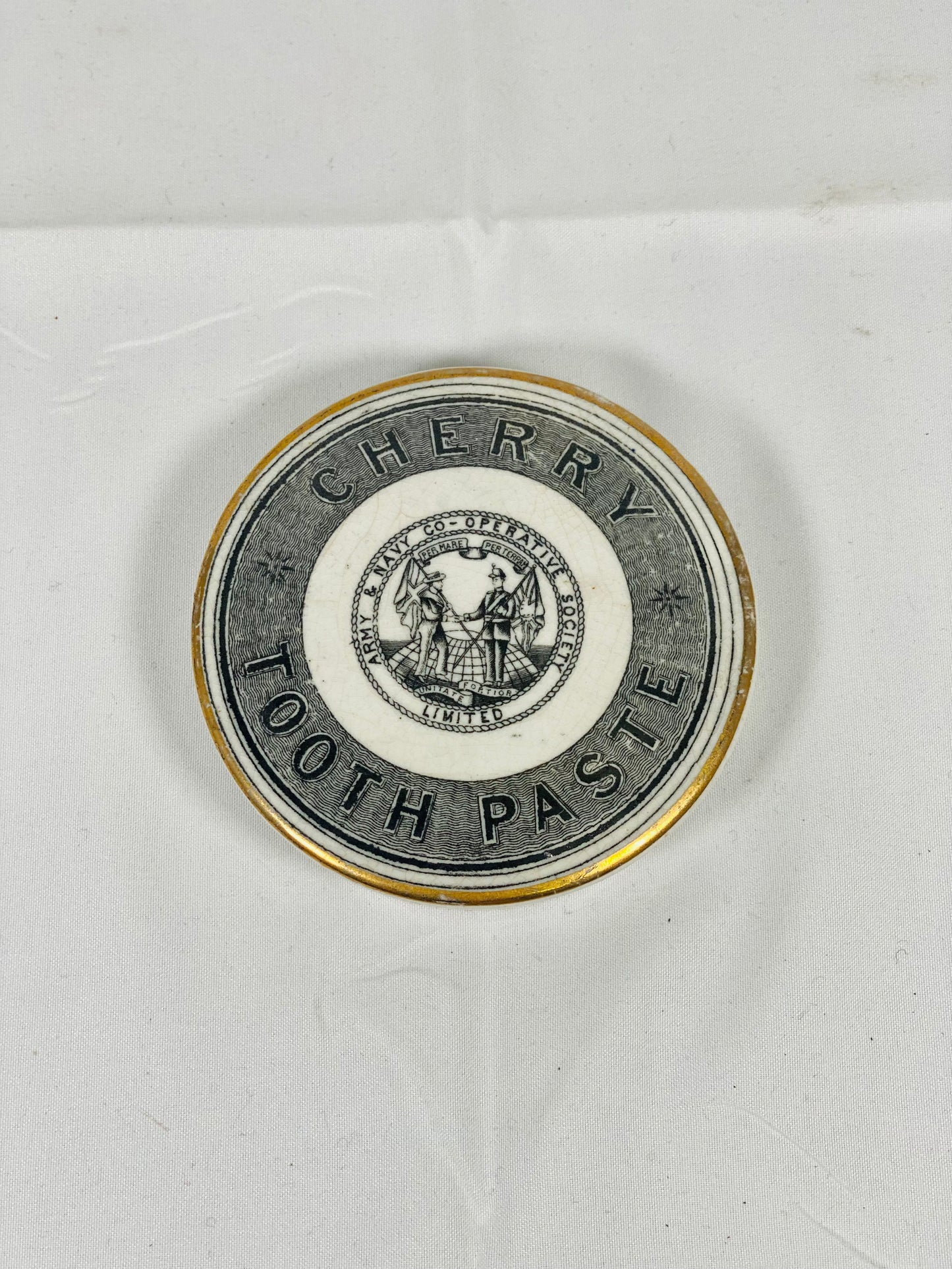 Tapa de bote de pasta de dientes con borde dorado, de la Sociedad Cooperativa del Ejército y la Marina, de cerámica victoriana de finales del siglo XIX, con diseño de cereza