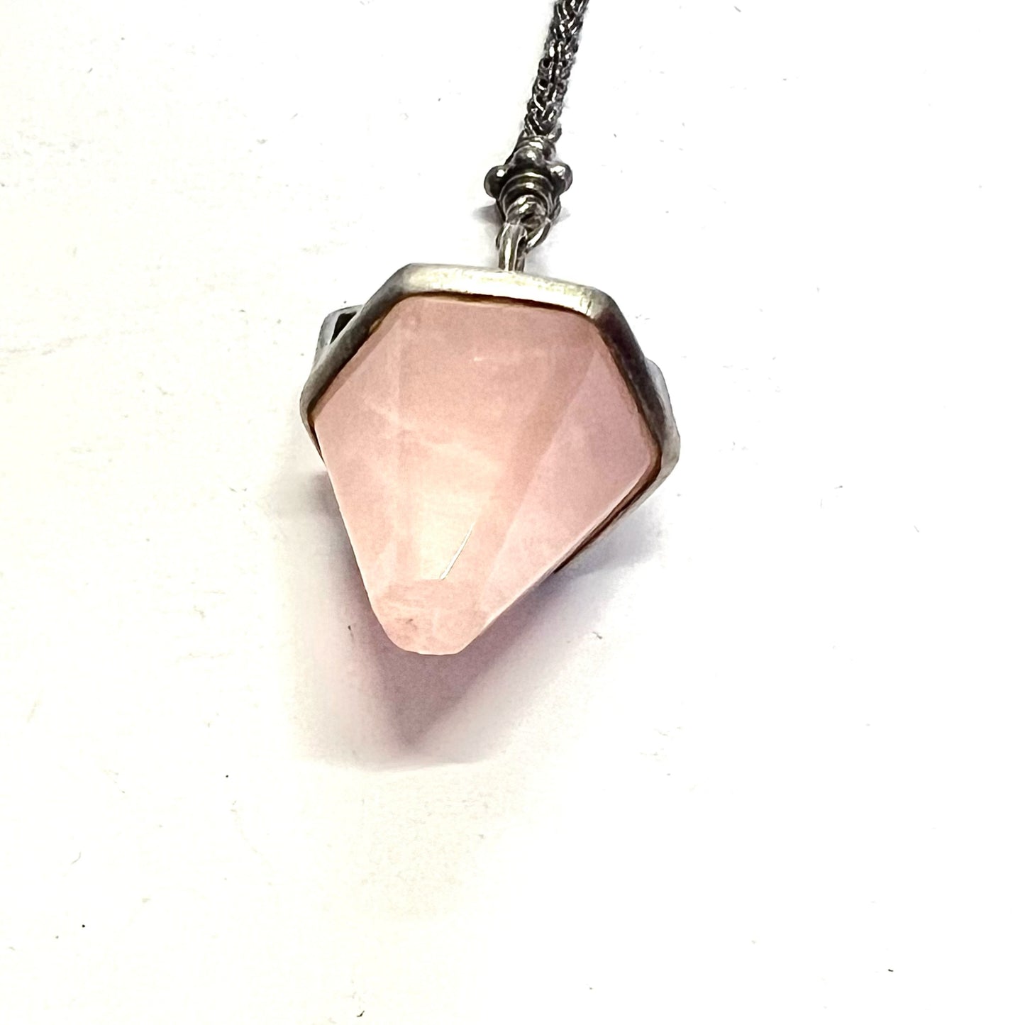 Rose quartz charm suspended from a sterling silver chain with T-bar