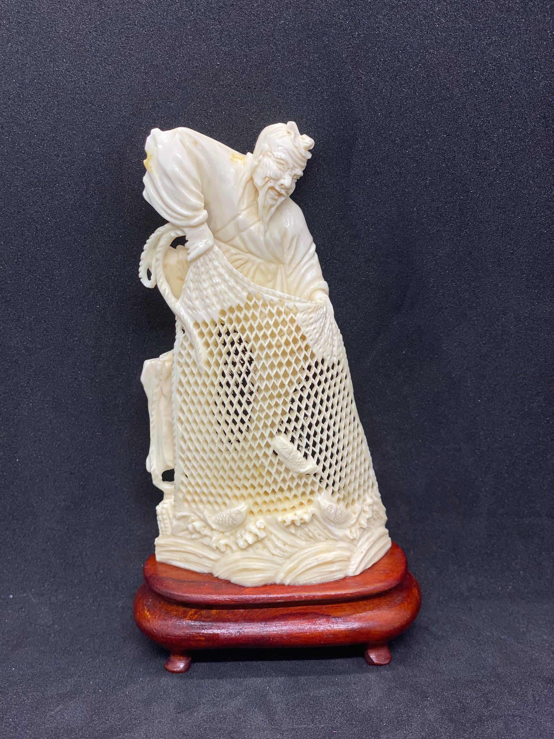 Small ivory figurine of fisherman holding net